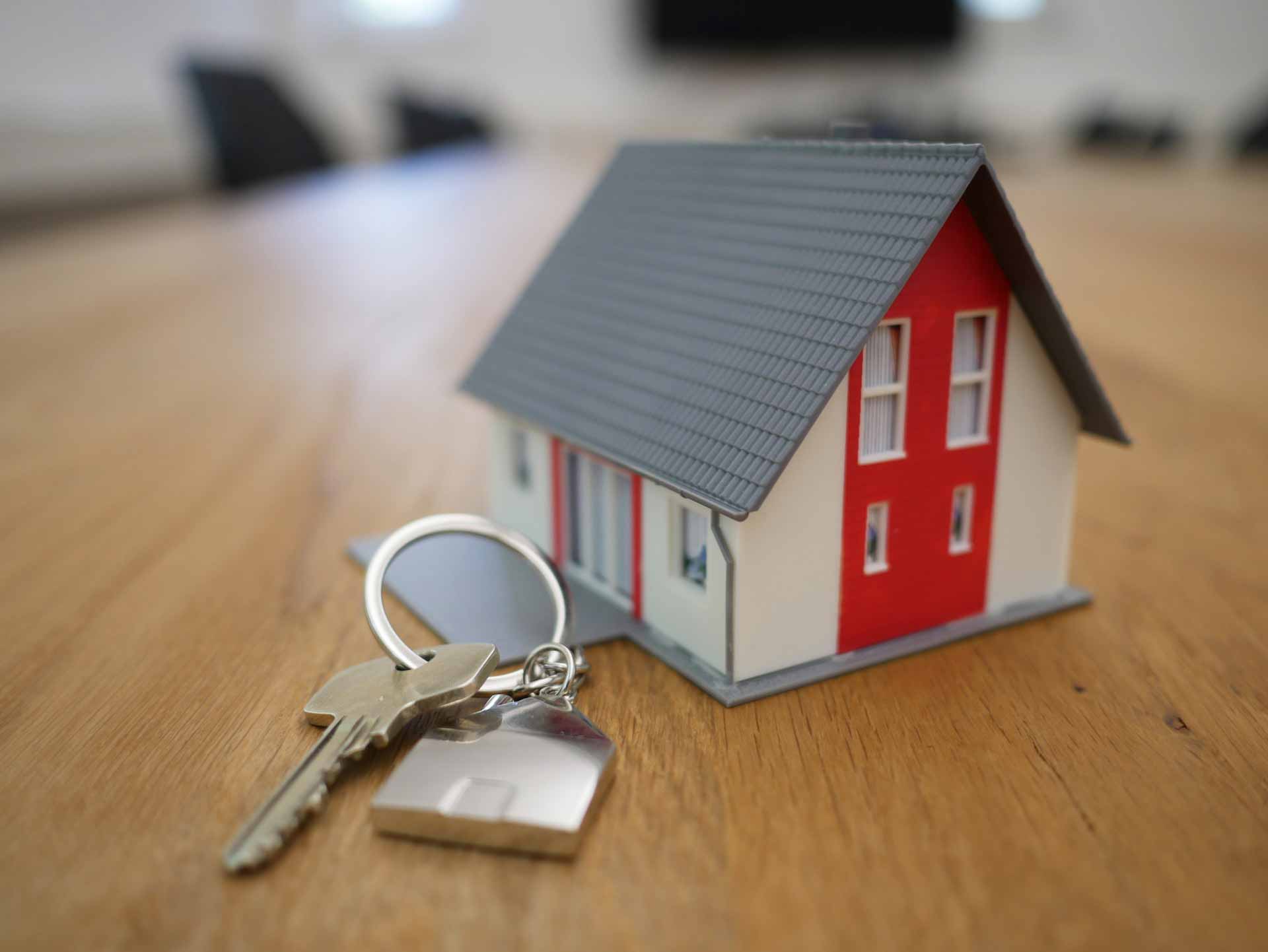 Small toy house sitting on table next to house keys